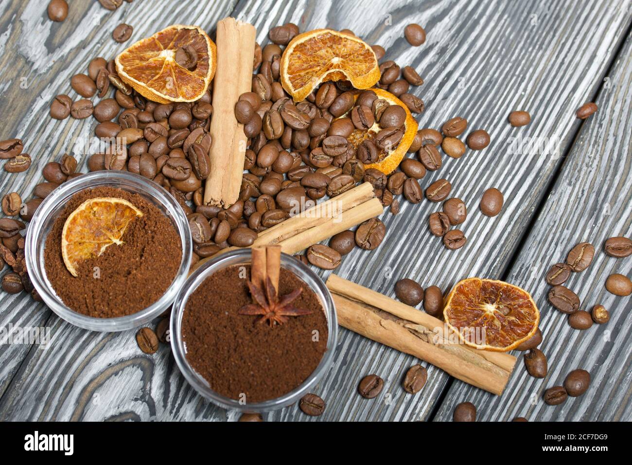 Chicchi di caffè. Caffè macinato in contenitori e spezie. Su una superficie di tavole di pino spazzolato dipinte in bianco e nero. Foto Stock