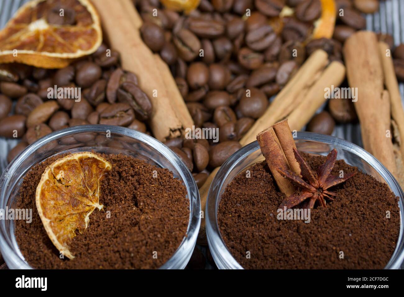 Chicchi di caffè. Caffè macinato in contenitori e spezie. Su una superficie di tavole di pino spazzolato dipinte in bianco e nero. Foto Stock
