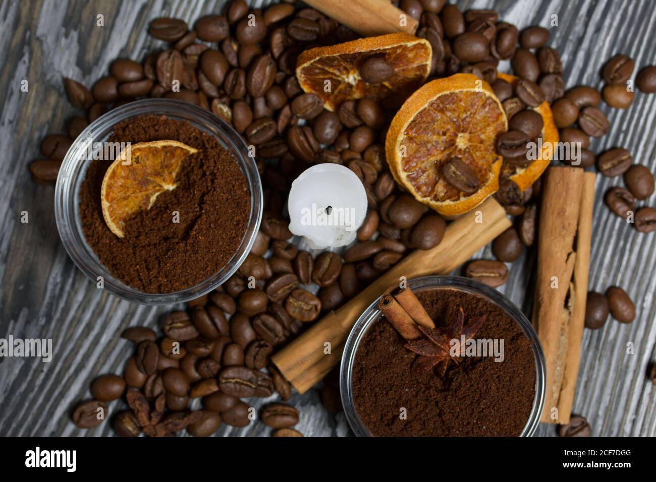 Chicchi di caffè su tela ruvida e stub di candela. Caffè macinato in contenitori e spezie. Su una superficie di tavole di pino spazzolato dipinte in bianco e nero. Foto Stock
