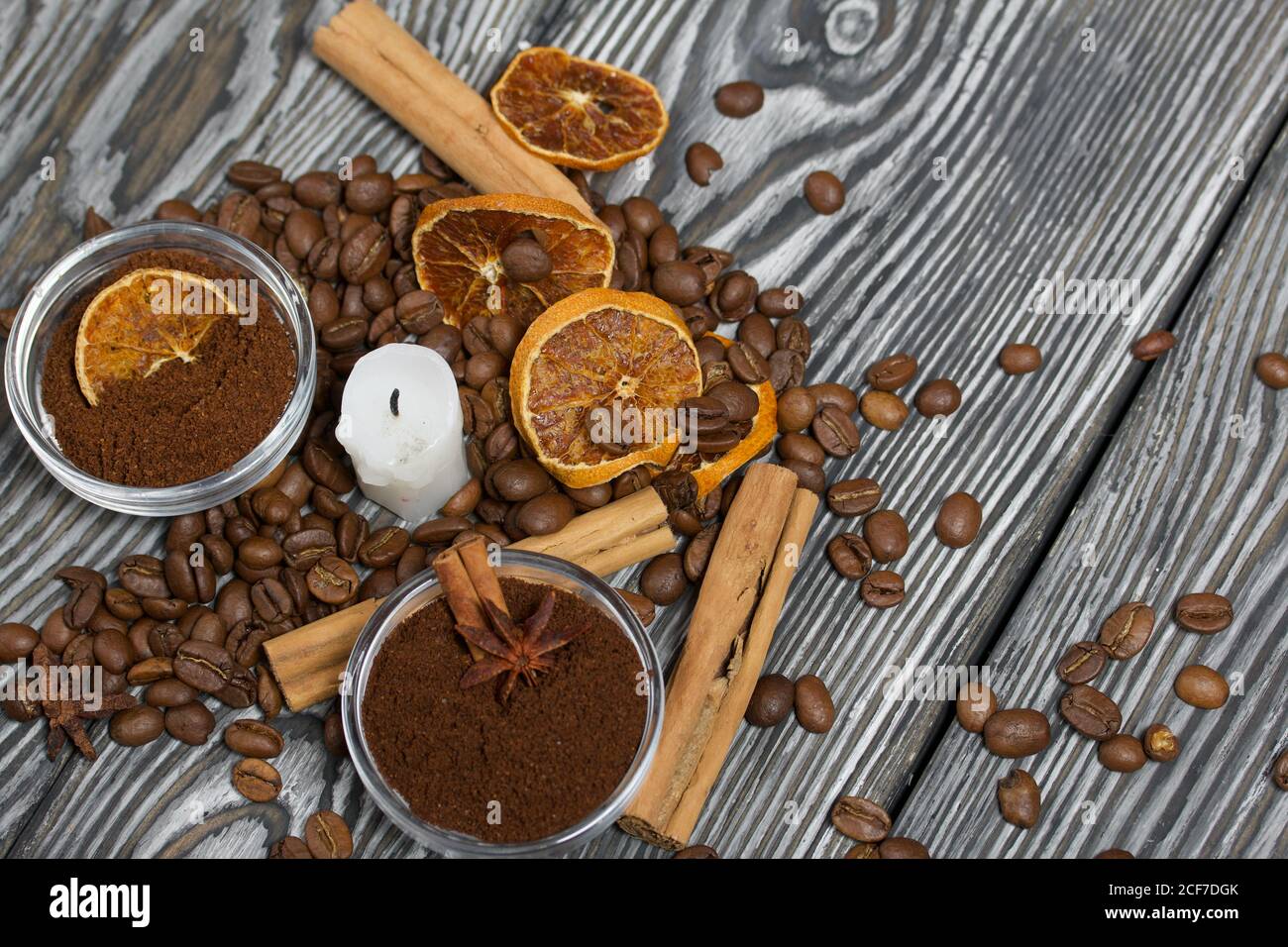 Chicchi di caffè su tela ruvida e stub di candela. Caffè macinato in contenitori e spezie. Su una superficie di tavole di pino spazzolato dipinte in bianco e nero. Foto Stock