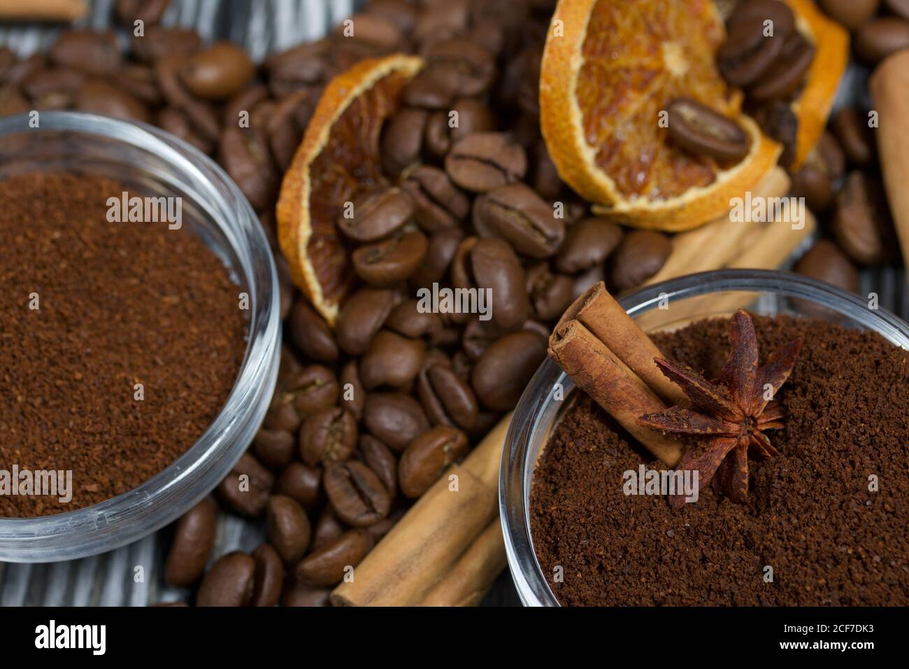 Chicchi di caffè. Caffè macinato in contenitori e spezie. Su una superficie di tavole di pino spazzolato dipinte in bianco e nero. Foto Stock