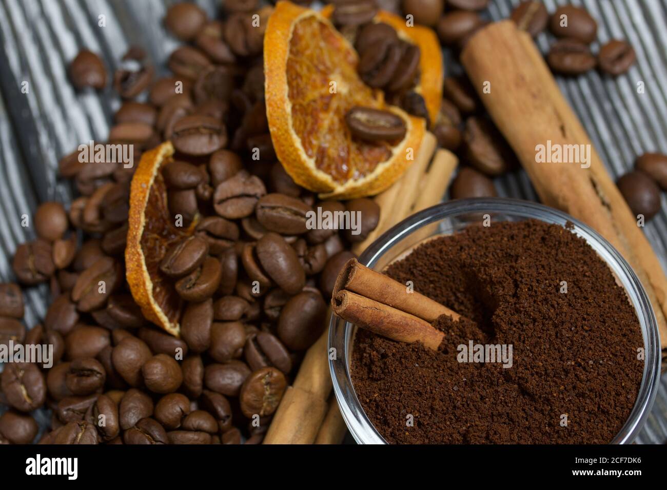 Chicchi di caffè e spezie. Contenitore del caffè macinato. Su una superficie di tavole di pino spazzolato dipinte in bianco e nero. Foto Stock