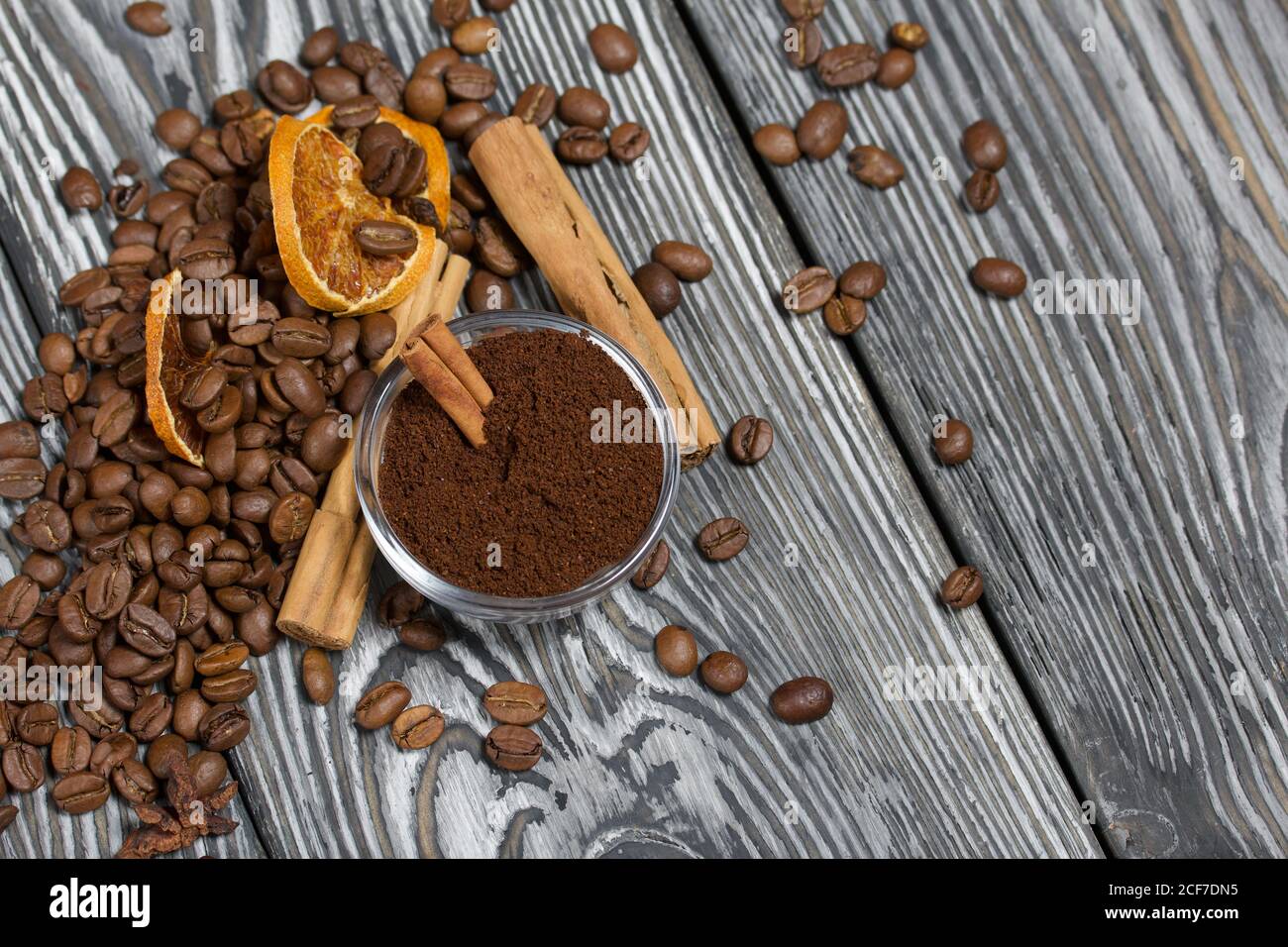 Chicchi di caffè e spezie. Contenitore del caffè macinato. Su una superficie di tavole di pino spazzolato dipinte in bianco e nero. Foto Stock