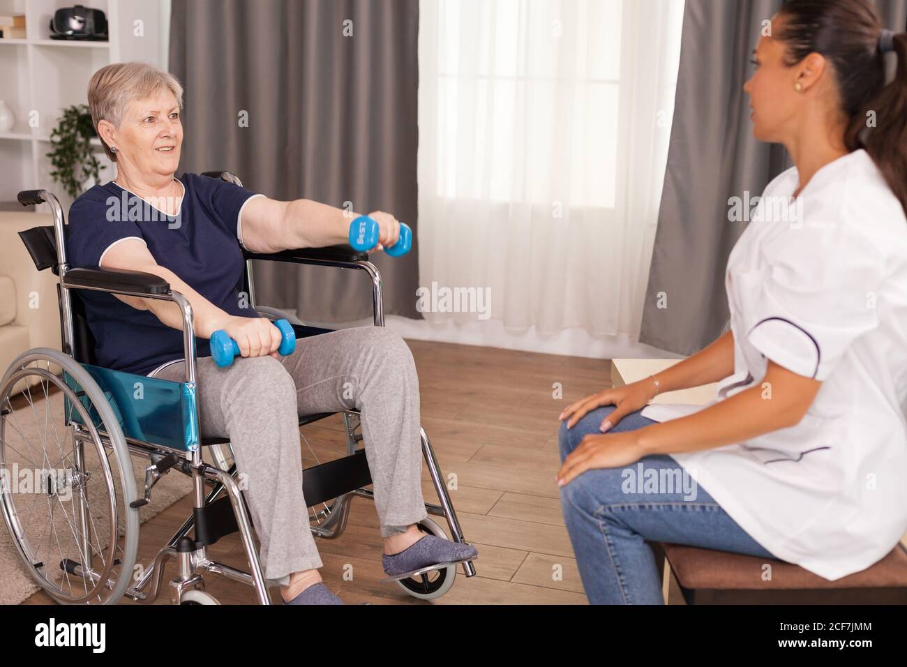 Dottore che aiuta la donna con disabilità a recuperare il muscolo delle sue braccia. Disabile anziano ricoverato infermiera di aiuto professionale, cura di casa di riposo e riabilitazione Foto Stock