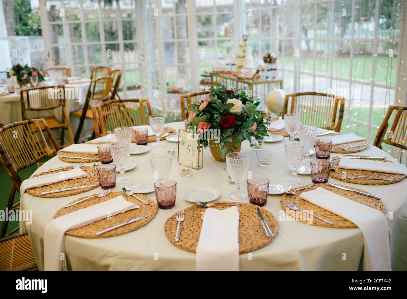 Bouquet di fiori unico e semplice in vaso su un tavolo festoso decorato con vetreria nel ristorante Foto Stock