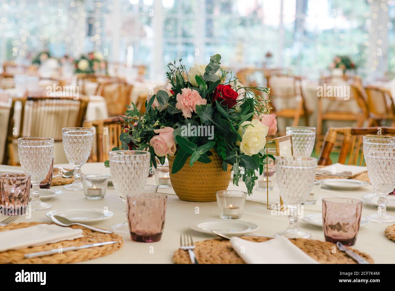 Bouquet di fiori unico e semplice in vaso su un tavolo festoso decorato con vetreria nel ristorante Foto Stock
