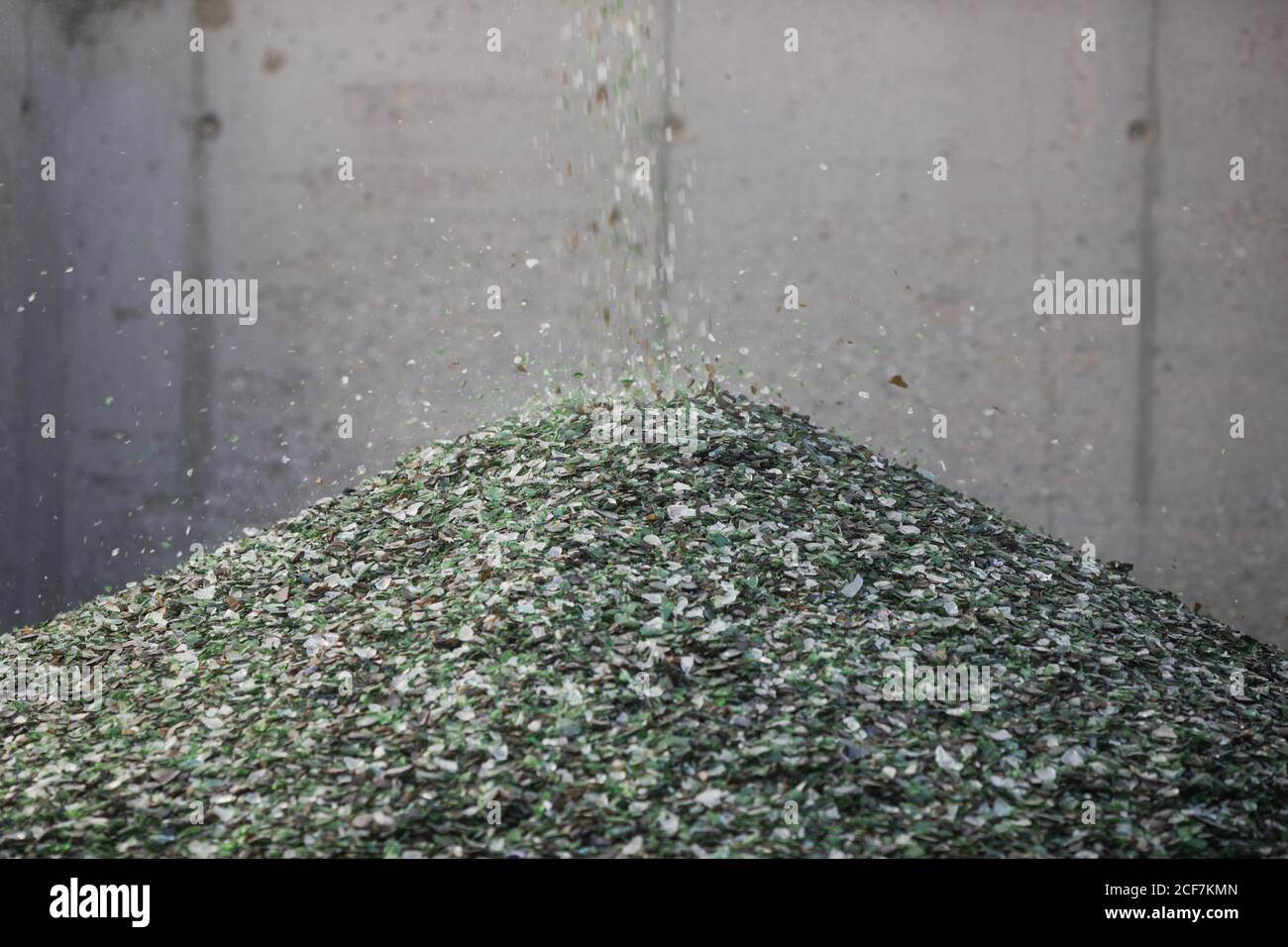 Dettagli con frammenti di vetro che cadono da un nastro trasportatore su una pila in un impianto di riciclaggio del vetro. Foto Stock