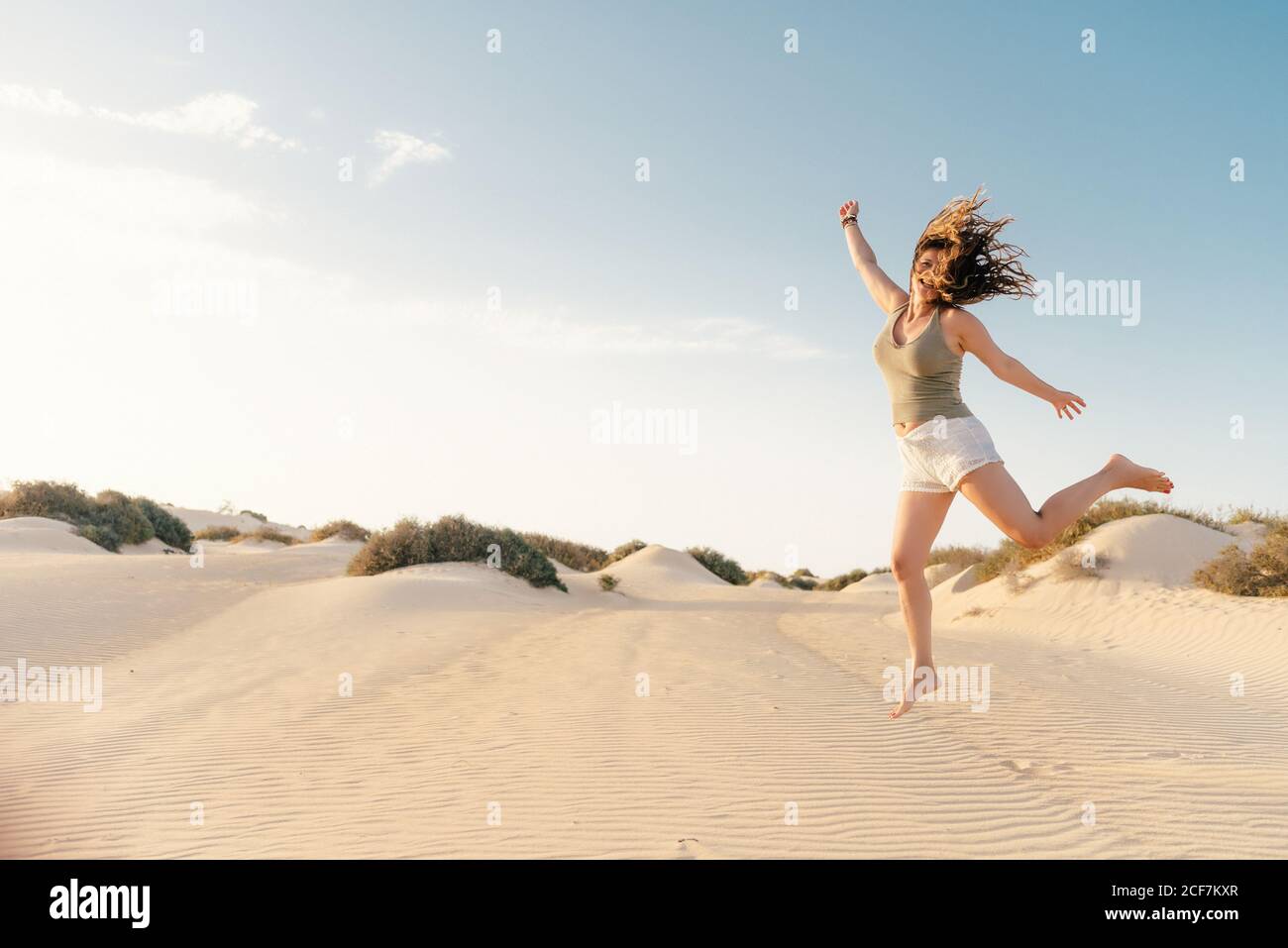 Donna attiva che corre nel deserto asciutto a piedi nudi Foto Stock