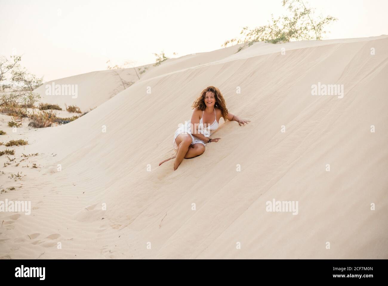 Donna seduta sulla sabbia nel deserto Foto Stock