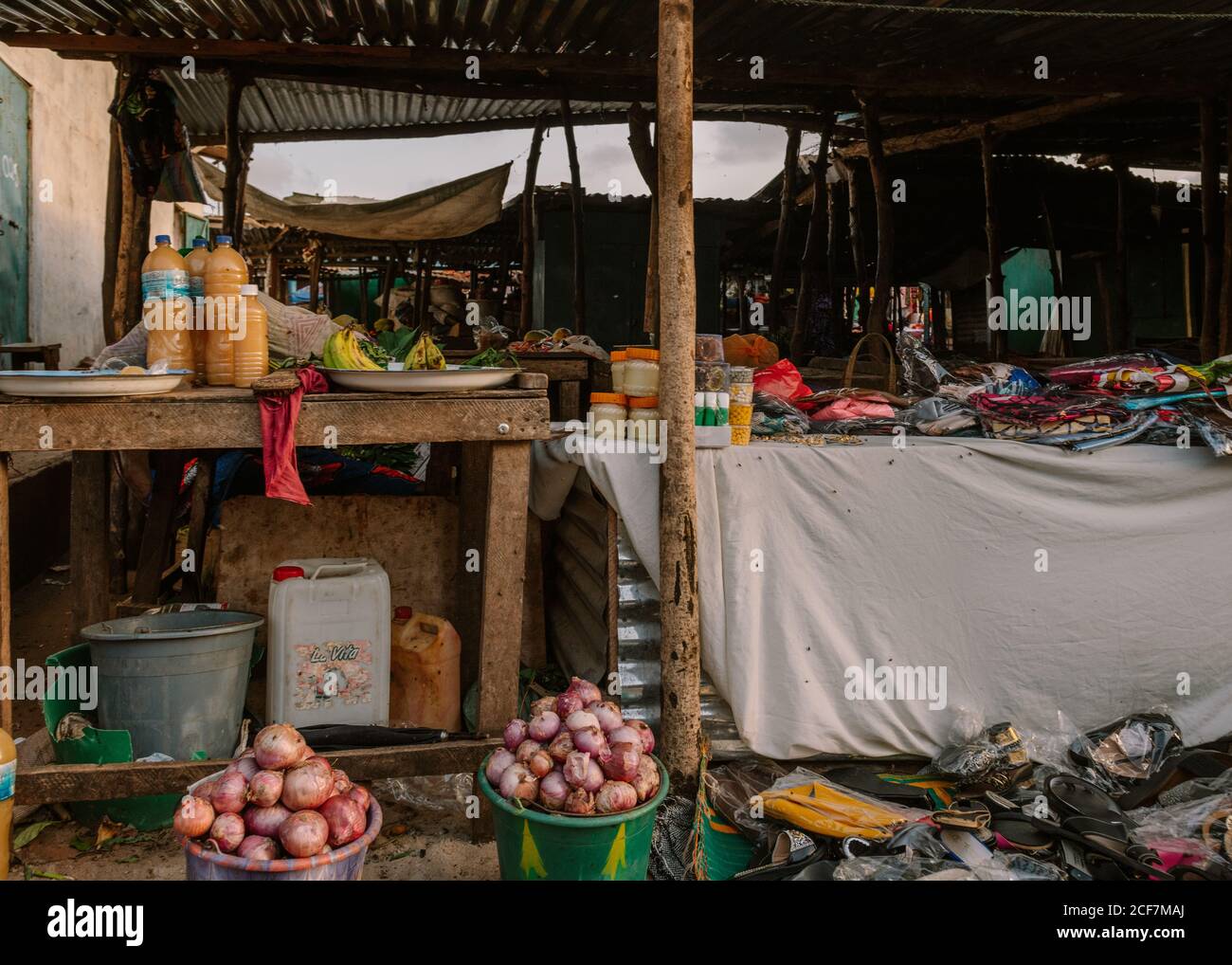 Gambia, Africa - 3 agosto 2019: Stalla con diversi cibi e bevande naturali tradizionali anche con vestiti e cose sotto il tetto nel bazaar di strada Foto Stock
