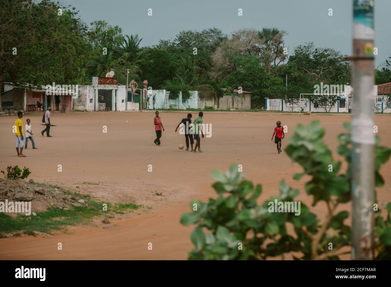 Gambia, Africa - 5 agosto 2019: I ragazzi poveri neri giocano a calcio con piacere a terra in un quartiere spazioso di giorno Foto Stock