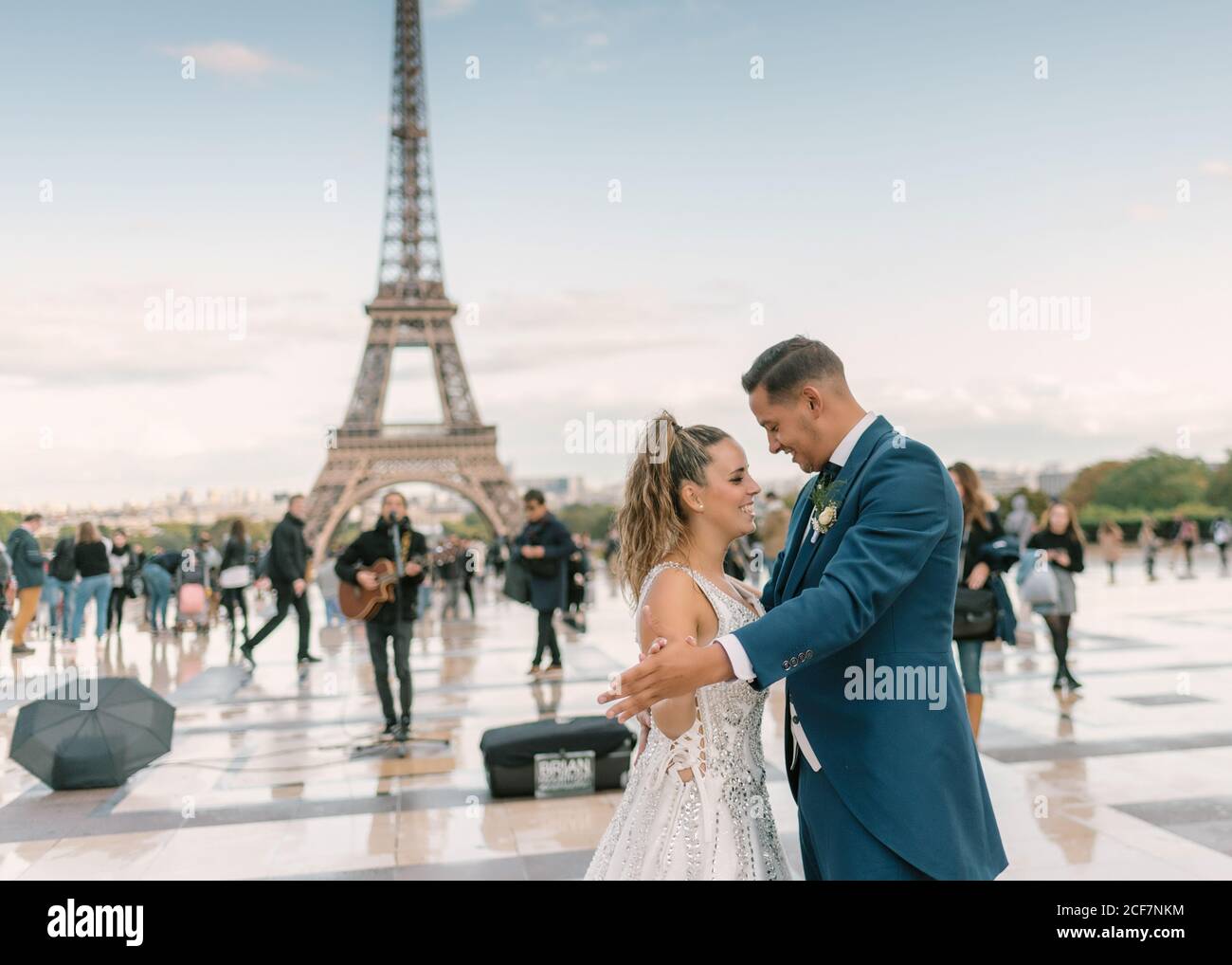 Sposo in abito da sposa blu in abito da sposa bianco avere danza lenta sorridente e guardarsi l'un l'altro con Torre Eiffel sullo sfondo a Parigi Foto Stock