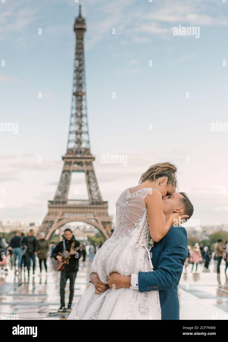 Sposo in abito da sposa blu in abito da sposa bianco Baciando con passione con la Torre Eiffel sullo sfondo a Parigi Foto Stock