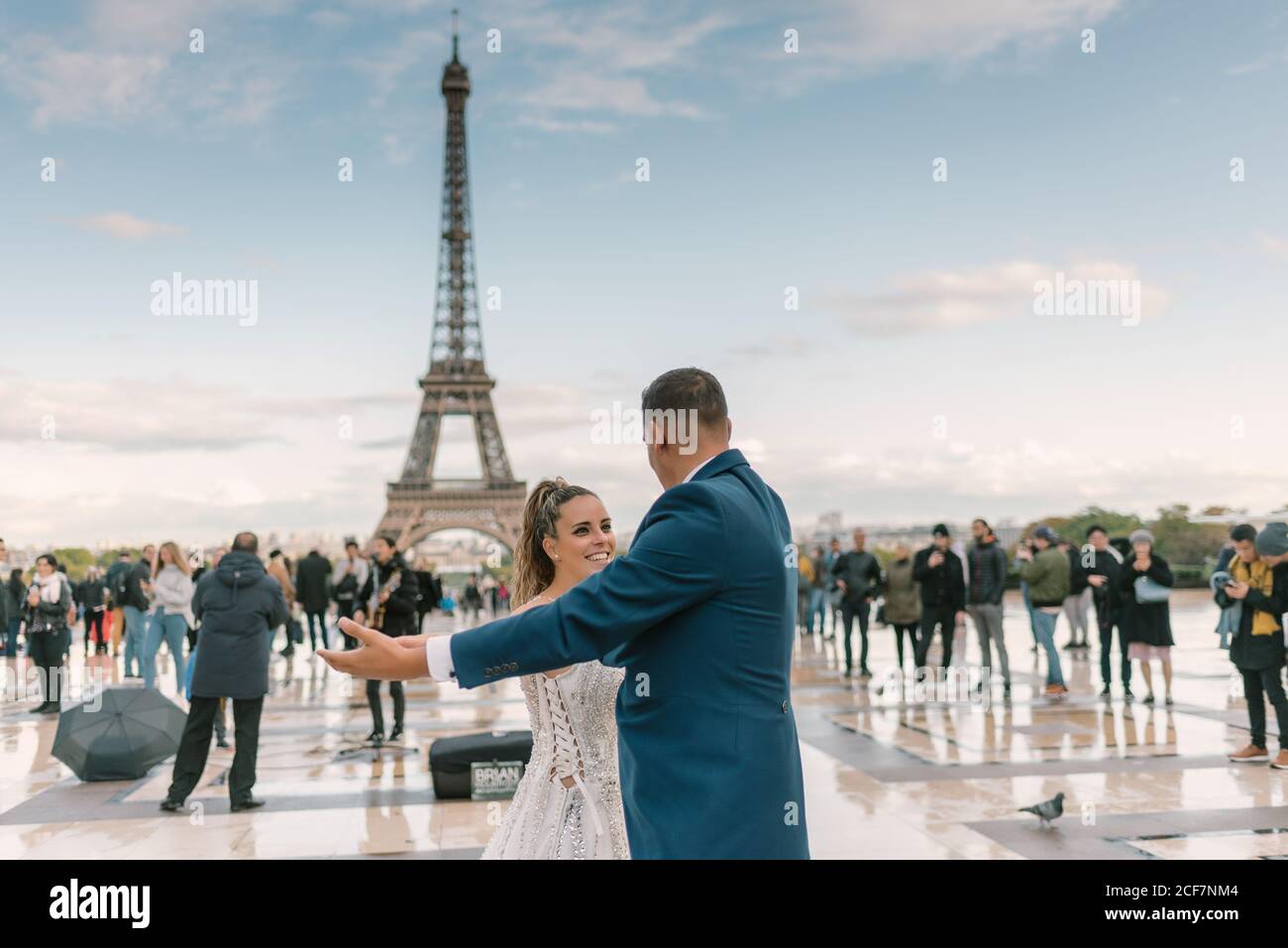 Sposo in abito da sposa blu in abito da sposa bianco avere danza lenta sorridente e guardarsi l'un l'altro con Torre Eiffel sullo sfondo a Parigi Foto Stock