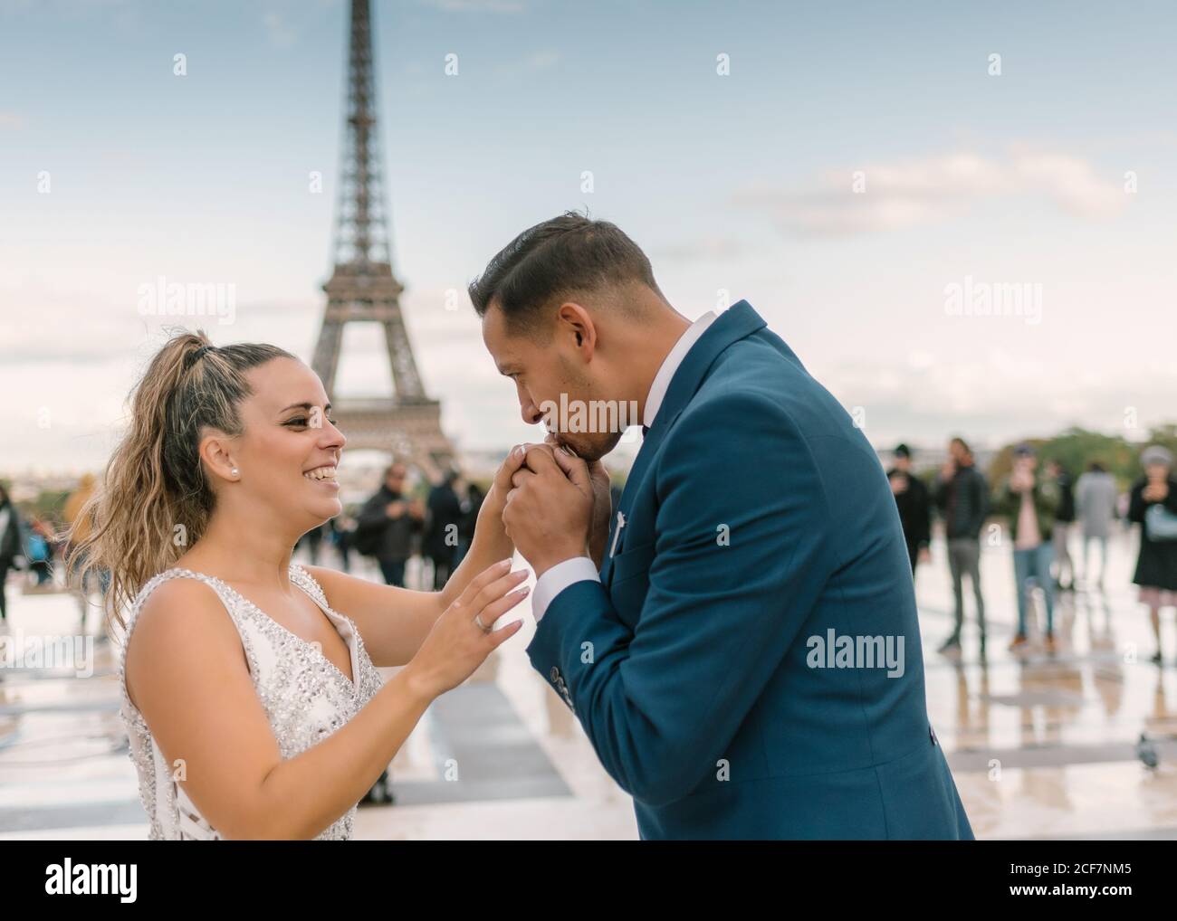 Sposo in abito da sposa blu in abito da sposa bianco Baciare la mano con la Torre Eiffel sullo sfondo a Parigi Foto Stock