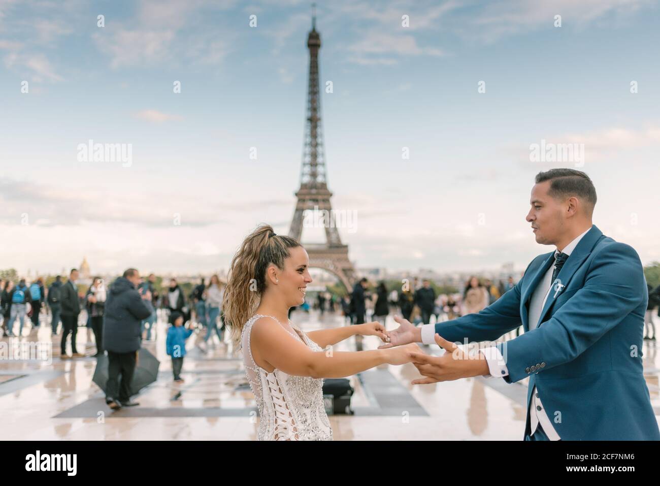 Sposo in abito da sposa blu in abito da sposa bianco avere danza lenta sorridente e guardarsi l'un l'altro con Torre Eiffel sullo sfondo a Parigi Foto Stock