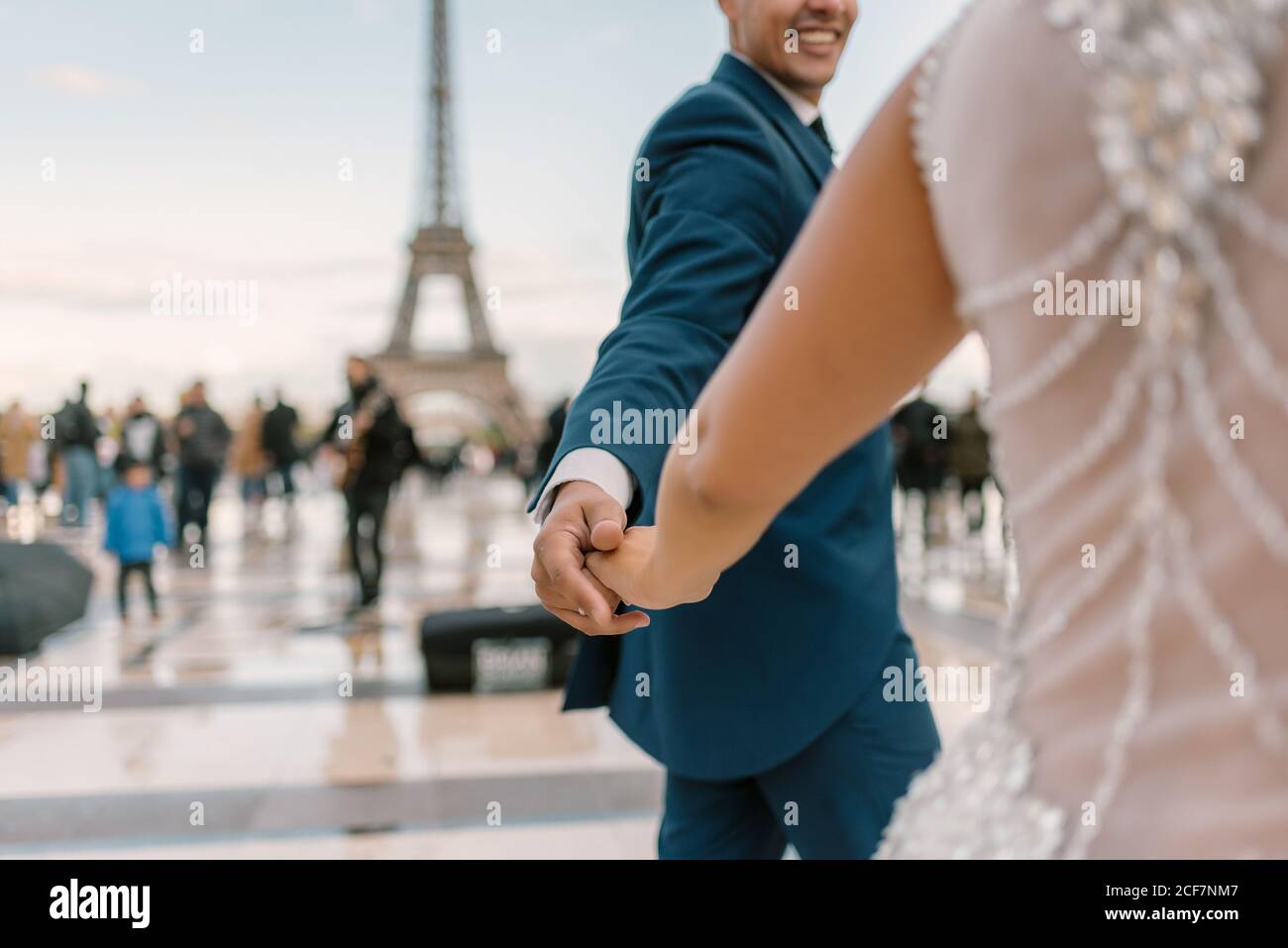 Sposo in abito da sposa blu in abito da sposa bianco avere danza lenta sorridente e guardarsi l'un l'altro con Torre Eiffel sullo sfondo a Parigi Foto Stock