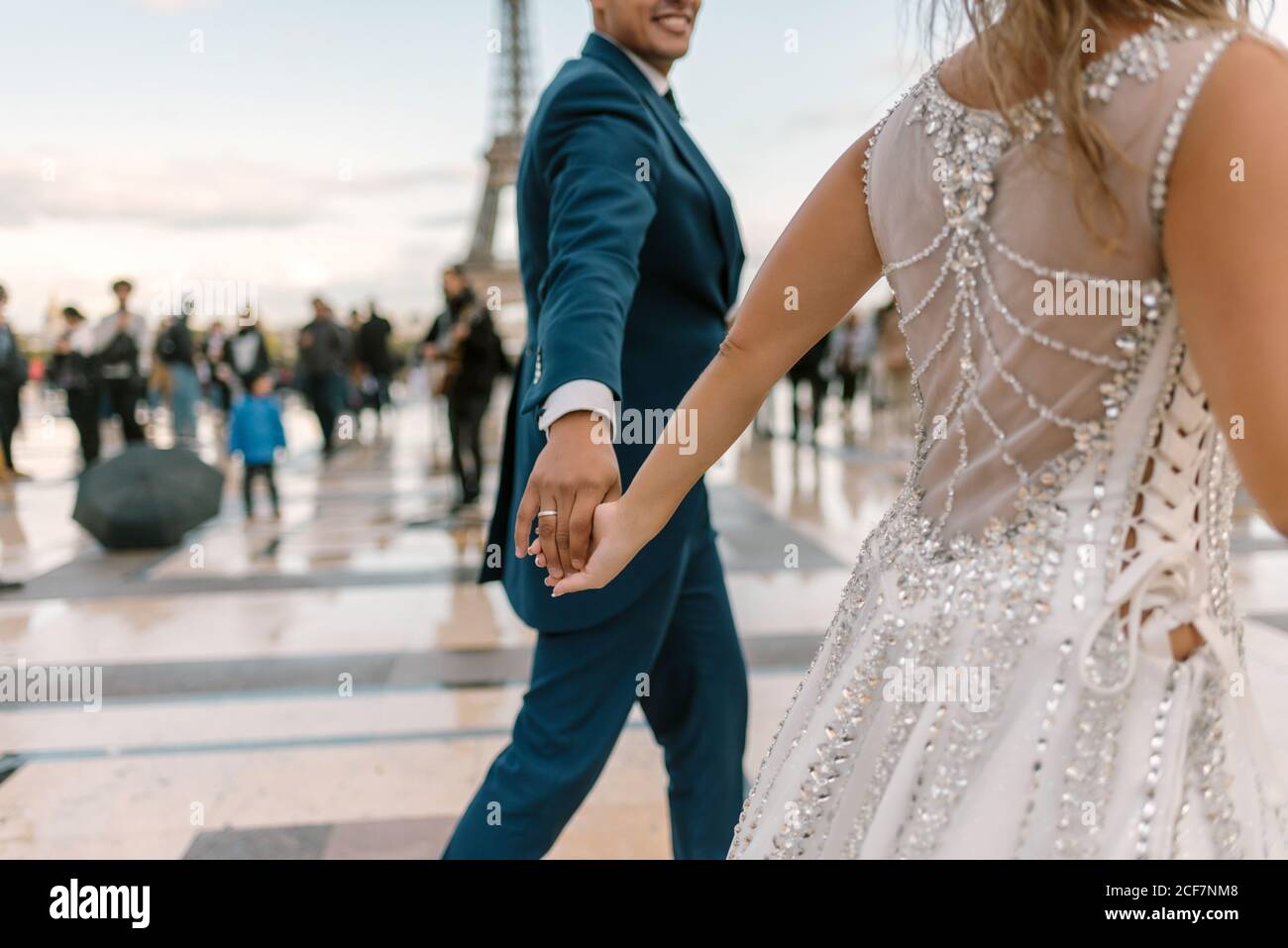 Sposo in abito da sposa blu in abito da sposa bianco avere danza lenta sorridente e guardarsi l'un l'altro con Torre Eiffel sullo sfondo a Parigi Foto Stock
