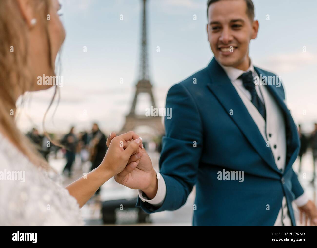 Sposo in abito da sposa blu in abito da sposa bianco avere danza lenta sorridente e guardarsi l'un l'altro con Torre Eiffel sullo sfondo a Parigi Foto Stock