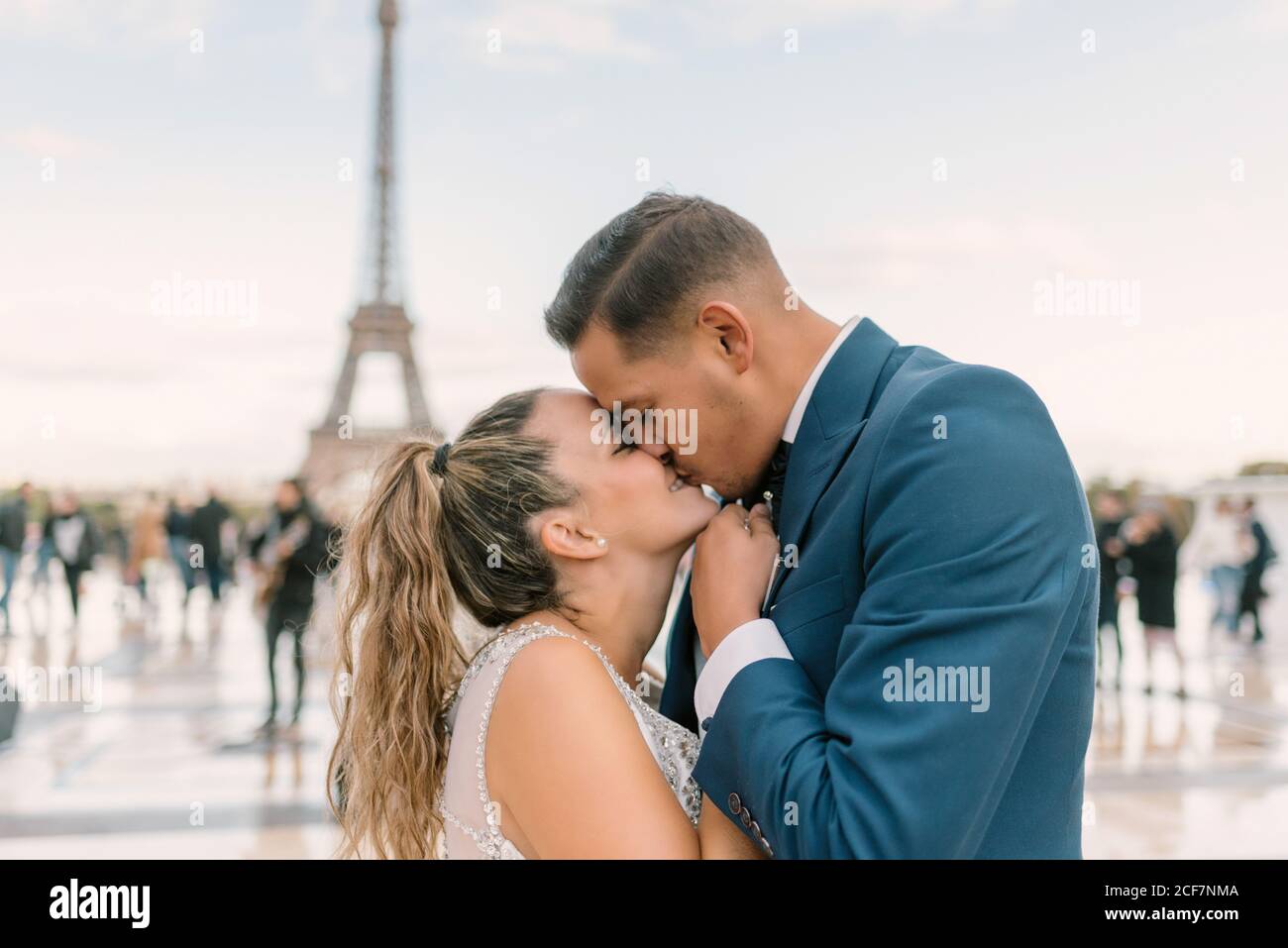 Sposo in abito da sposa blu in abito da sposa bianco Baciando con passione con la Torre Eiffel sullo sfondo a Parigi Foto Stock