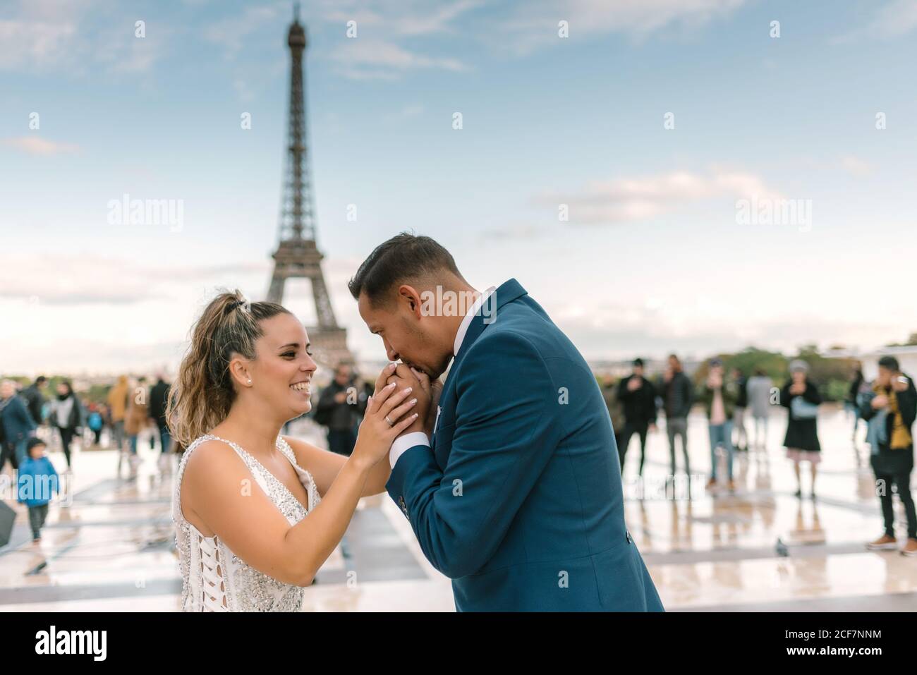 Sposo in abito da sposa blu in abito da sposa bianco Baciare la mano con la Torre Eiffel sullo sfondo a Parigi Foto Stock