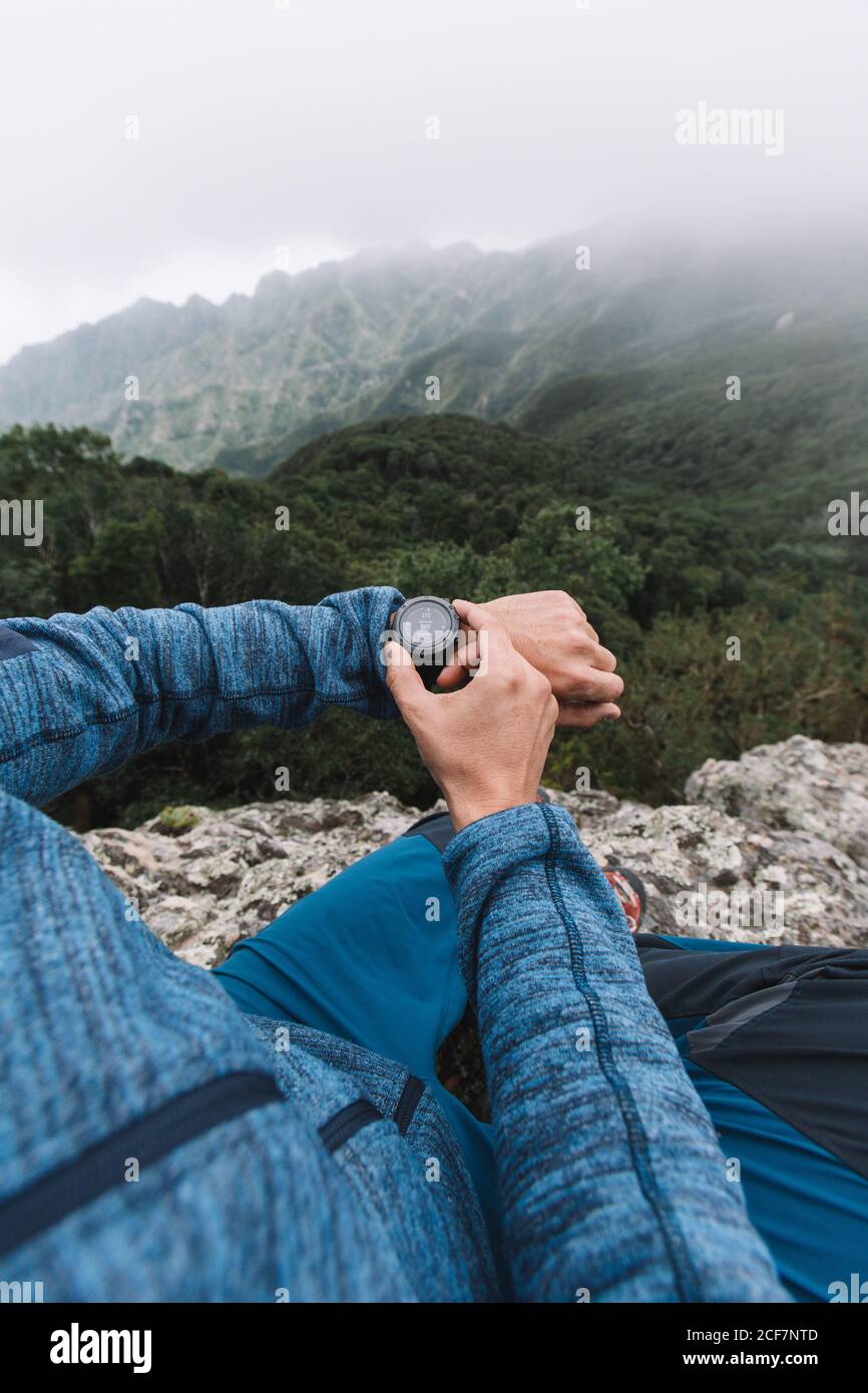 Vista in prima persona di una mano di raccolto di ragazzo che usa un orologio in montagna Foto Stock