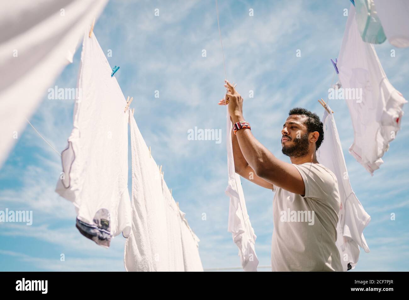 Diligente uomo etnico appeso t-shirt su corda Foto Stock