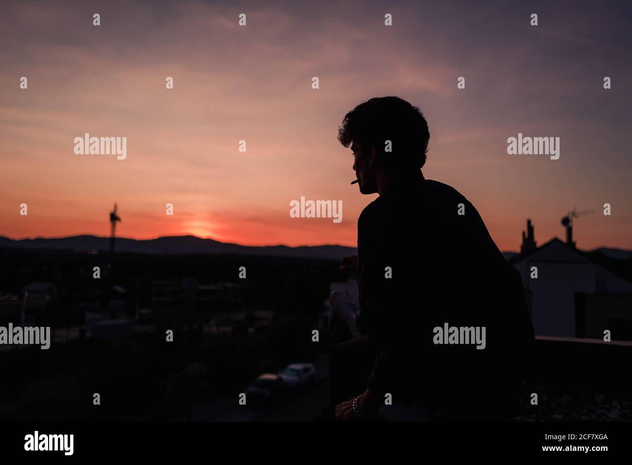 Giovane uomo che fuma sigaretta al tramonto Foto Stock