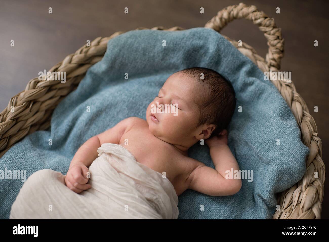 Vista dall'alto del neonato avvolto in un panno su cui poggiare soffice coperta e dormire in cesto di vimini al piano a. casa Foto Stock