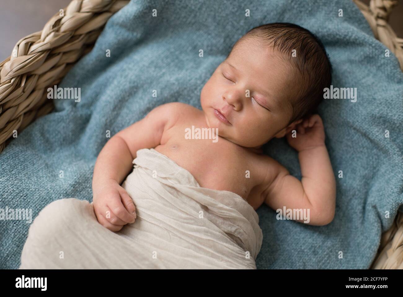Vista dall'alto del neonato avvolto in un panno su cui poggiare soffice coperta e dormire in cesto di vimini al piano a. casa Foto Stock