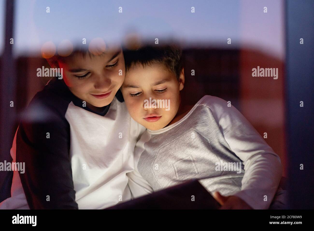 Carino fratelli guardare cartone animato su tablet insieme Foto Stock