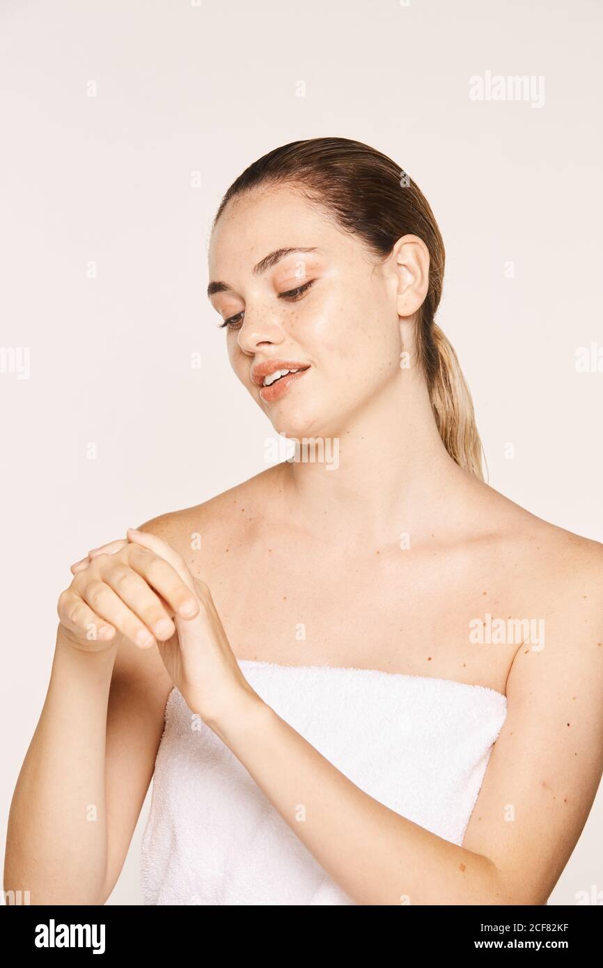 Donna felicissima che applica crema di recupero sulle mani Foto Stock