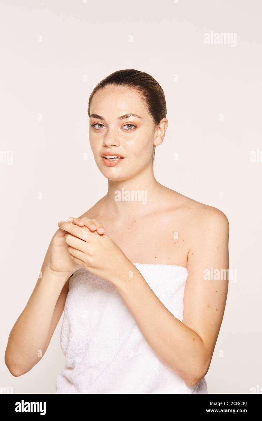 Donna felicissima che applica crema di recupero sulle mani Foto Stock