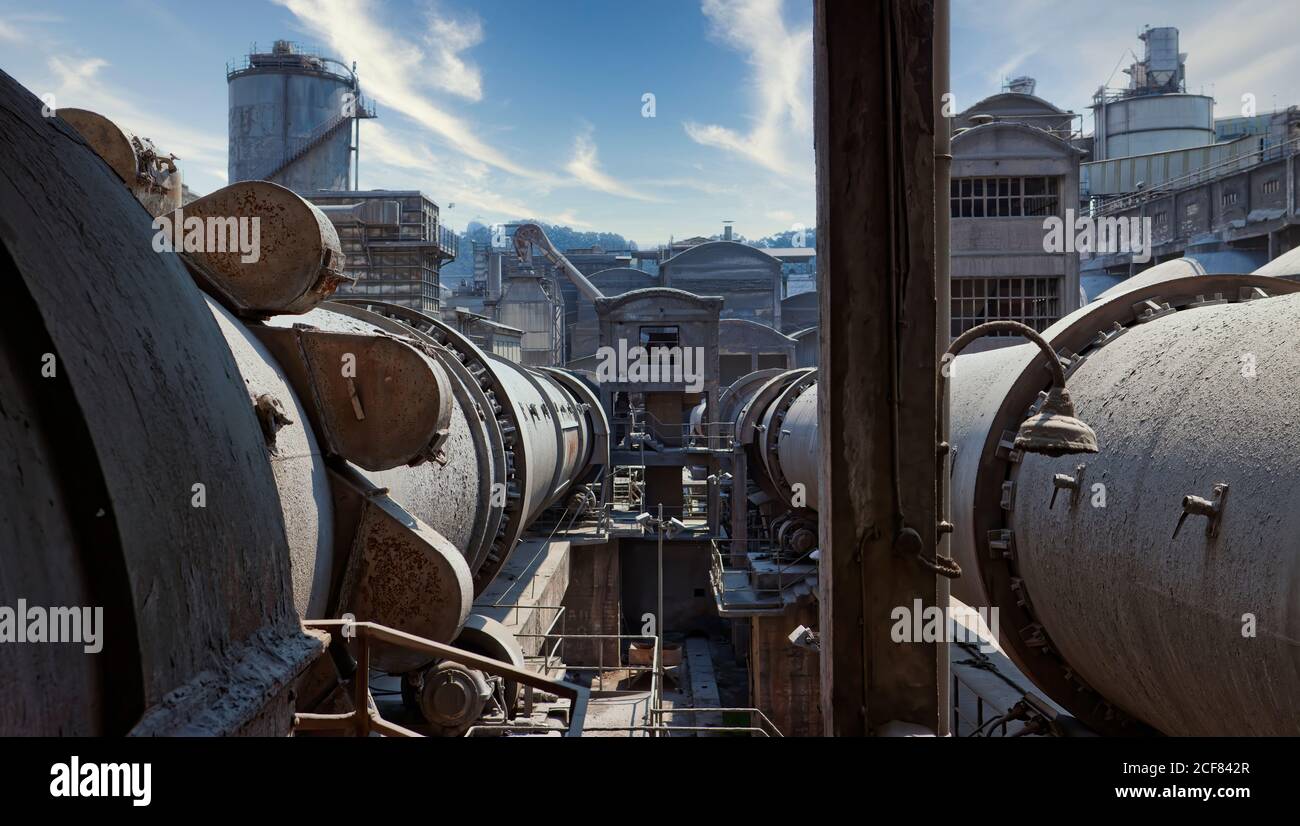 Vista di stoccaggio contenitori invecchiati con gas localizzati sul territorio di area industriale di fronte a torri d'acqua e abbandonato costruzione Foto Stock