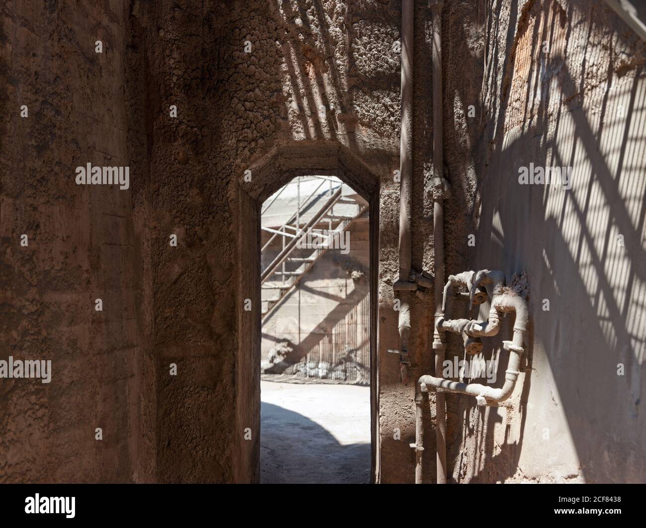 Corridoio industriale sporco con arco stretto di fronte scala in lontananza di fabbrica consumata durante il giorno con luce diurna dall'alto Foto Stock