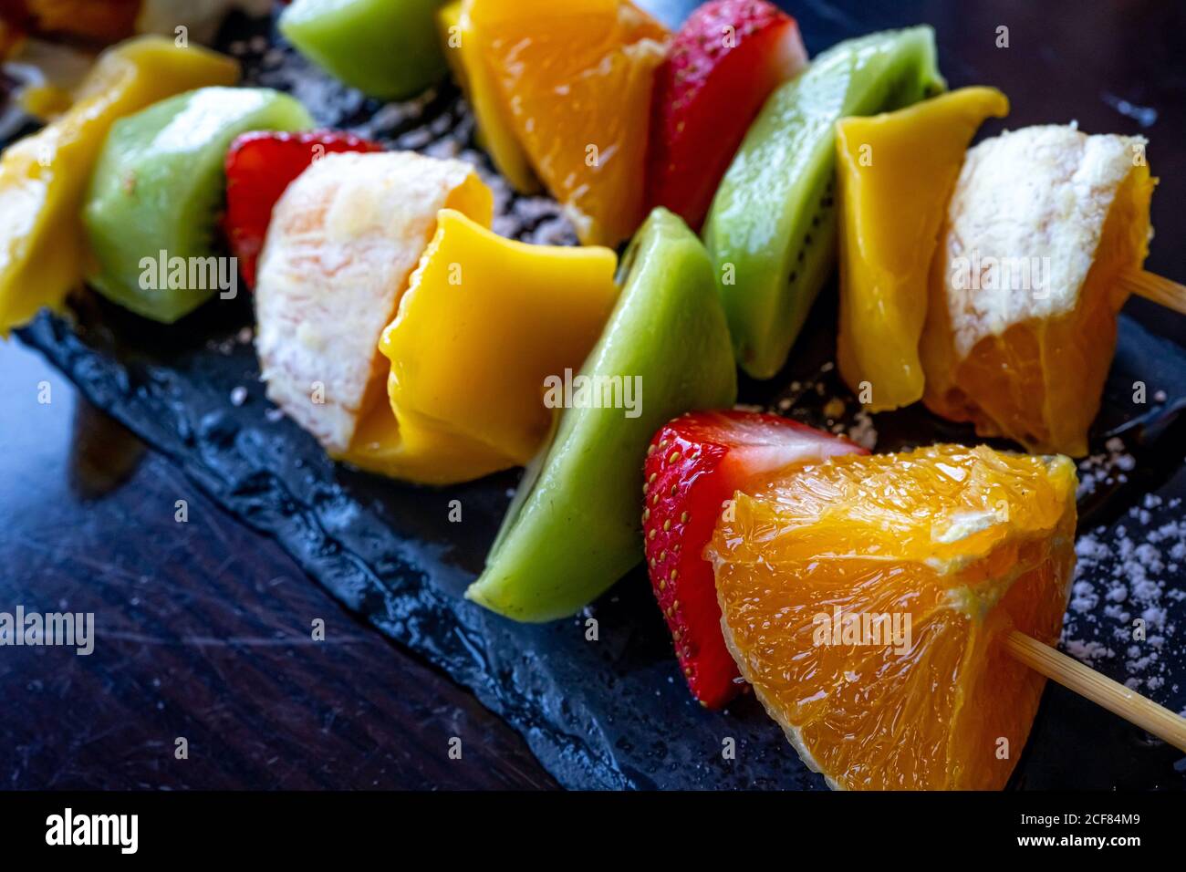 Kebab di frutta fatto di arance, fragole, Kiwi, Mango. Primo piano della macro. Messa a fuoco selettiva Foto Stock