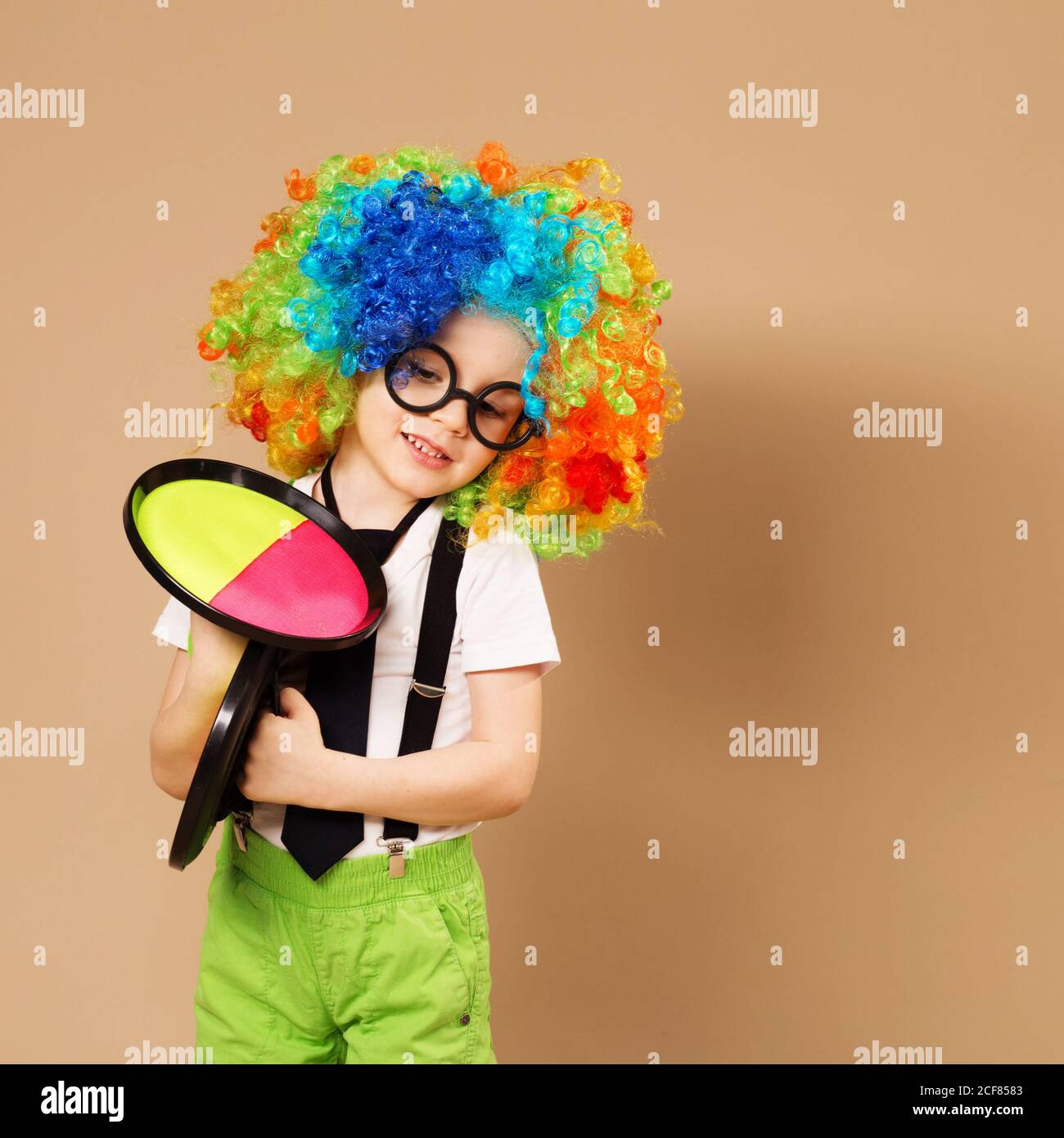 Bambini blitesome. Ritratto di ragazzo clown felice che indossa una grande  parrucca colorata al neon. Capretto in parrucca clown e occhiali che  giocano gioco della sfera di cattura Foto stock - Alamy
