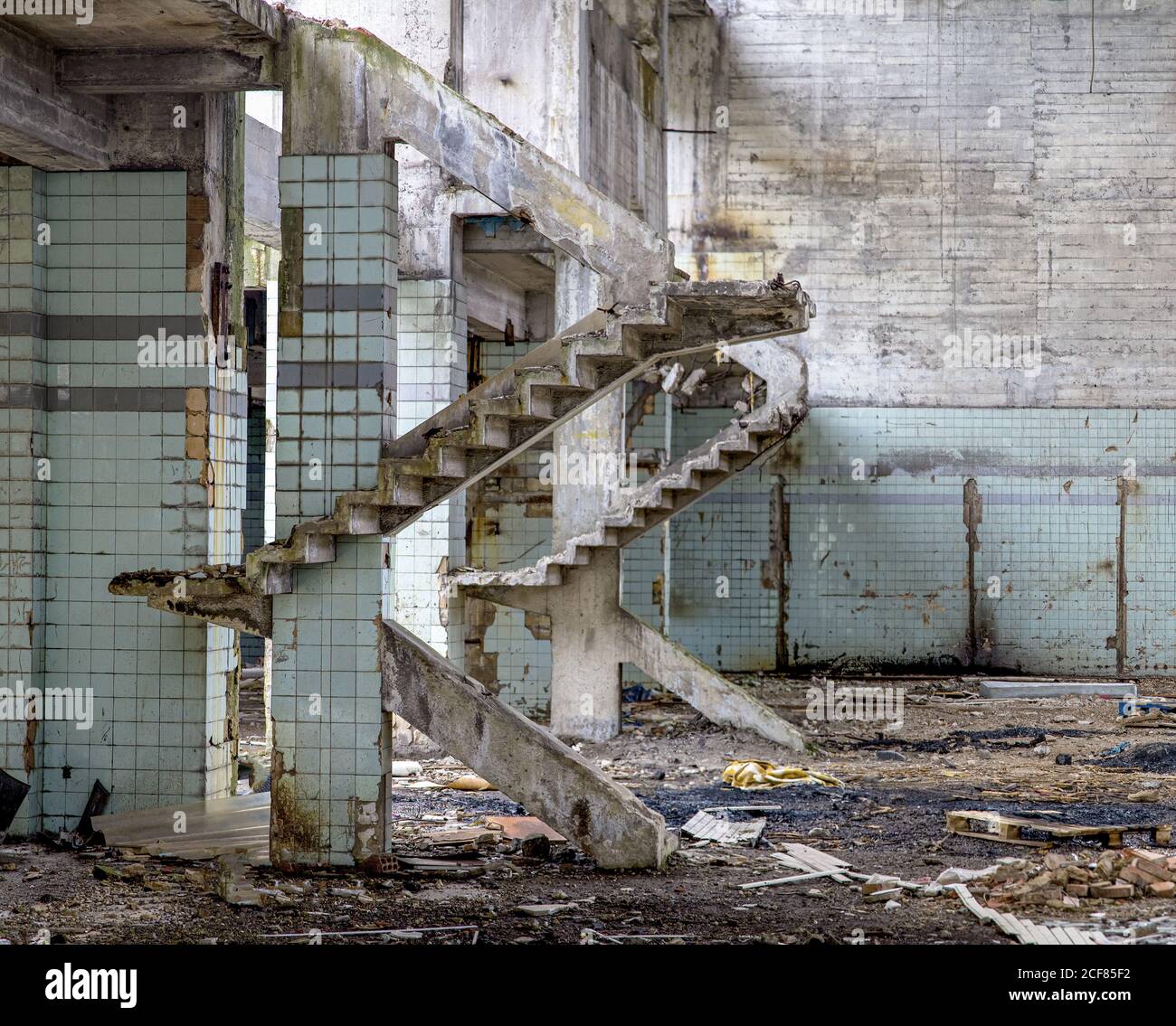 Muri in cemento e resti di scale in vecchio abbandonato industriale edificio con terreno disordinato Foto Stock