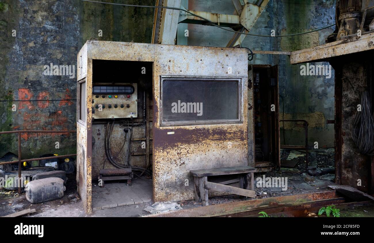 Cabina in metallo arrugginito con apparecchiature elettriche installate in vecchio edificio industriale con pareti grugnose Foto Stock