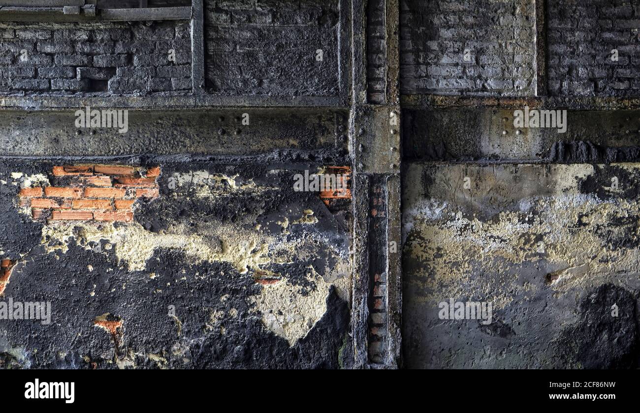 Muro di mattoni grugnosi con intonaco sporco sbriciolato situato all'interno invecchiato impianto industriale abbandonato Foto Stock