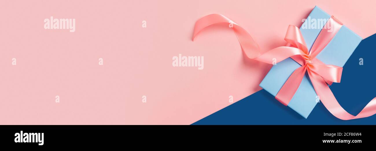 Banner Web di saluto con confezione regalo blu. Archi rosa. Spazio per il testo. Foto Stock