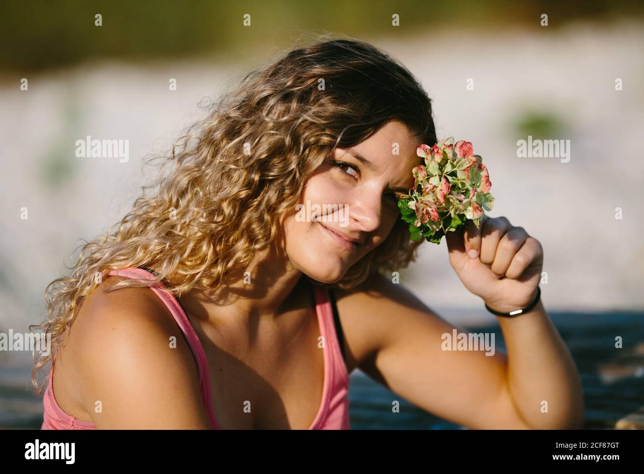 Donna deliziata in estate indossare godendo il sole durante il fine settimana sul lago e guardando la macchina fotografica Foto Stock