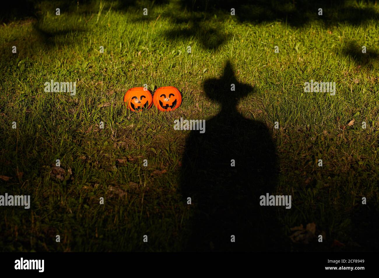 Immagine dell'ombra nera nel cappello sull'erba verde Con zucche giocattolo alla festa di Halloween Foto Stock