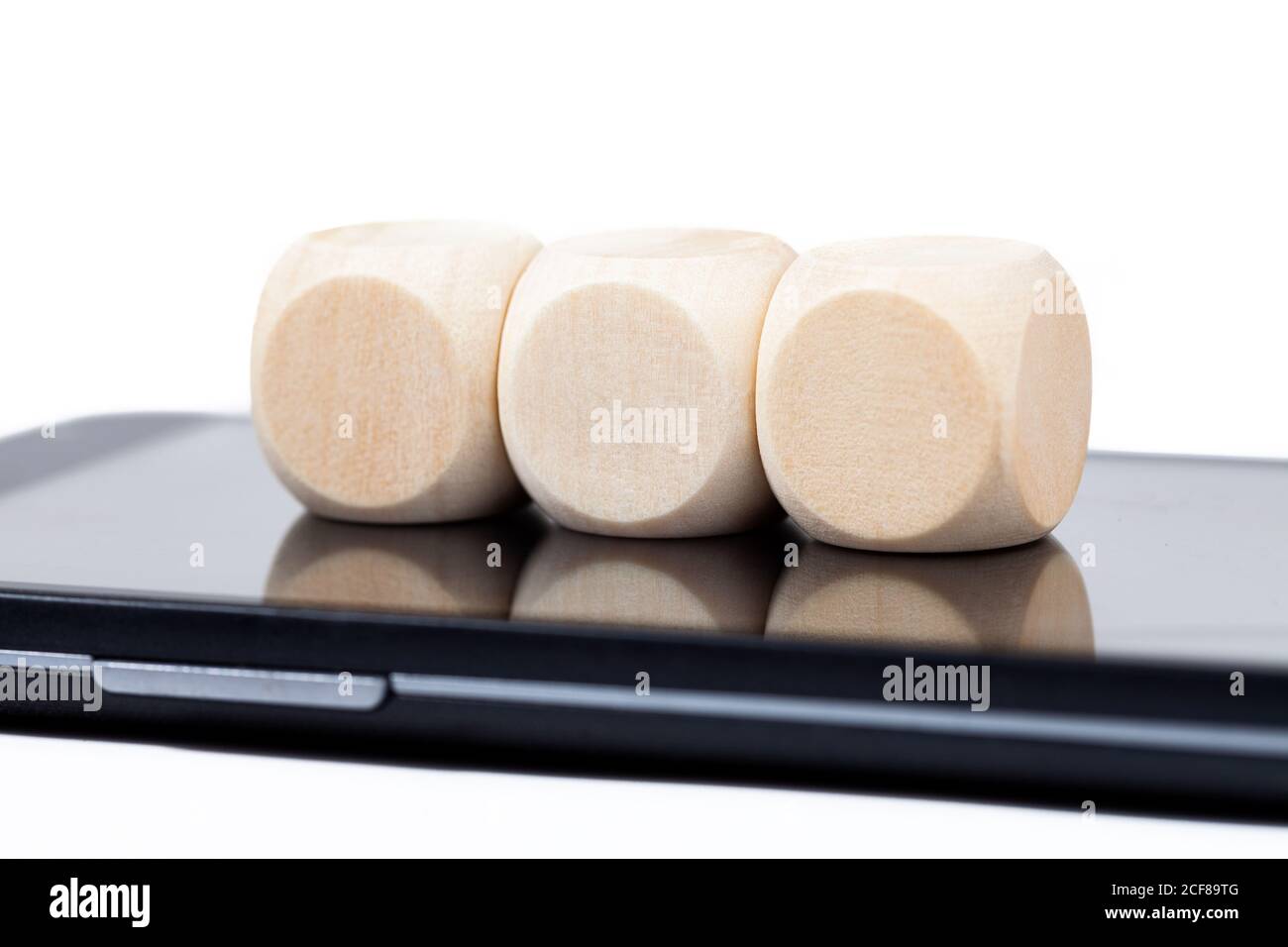 Tre cubi di legno vuoti che si stendono sullo schermo di uno smartphone. Dadi vuoti con spazio icone posizionato sul display di un telefono cellulare. 3 elementi, cubi tecnologici Foto Stock