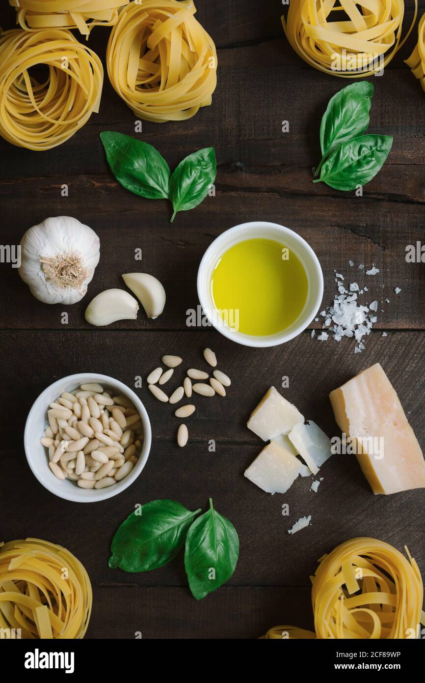 Vista dall'alto di erbe fresche e formaggio con olio e. tagliatelle pasta disporre in rustico tavolo di legno Foto Stock
