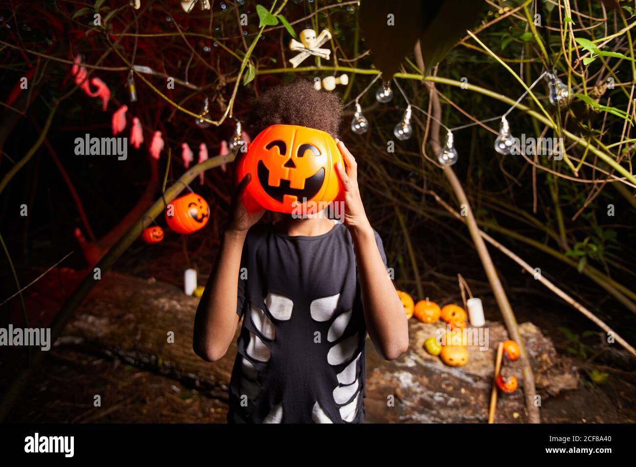 Ritratto di ragazzo africano che tiene la zucca giocattolo di fronte La sua faccia che ha divertimento alla festa di Halloween in scuro Foto Stock