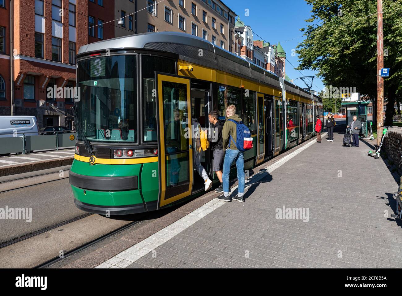 Gli adolescenti si fermano al tram alla fermata Karhupuisto del tram nel quartiere Kallio di Helsinki, Finlandia Foto Stock