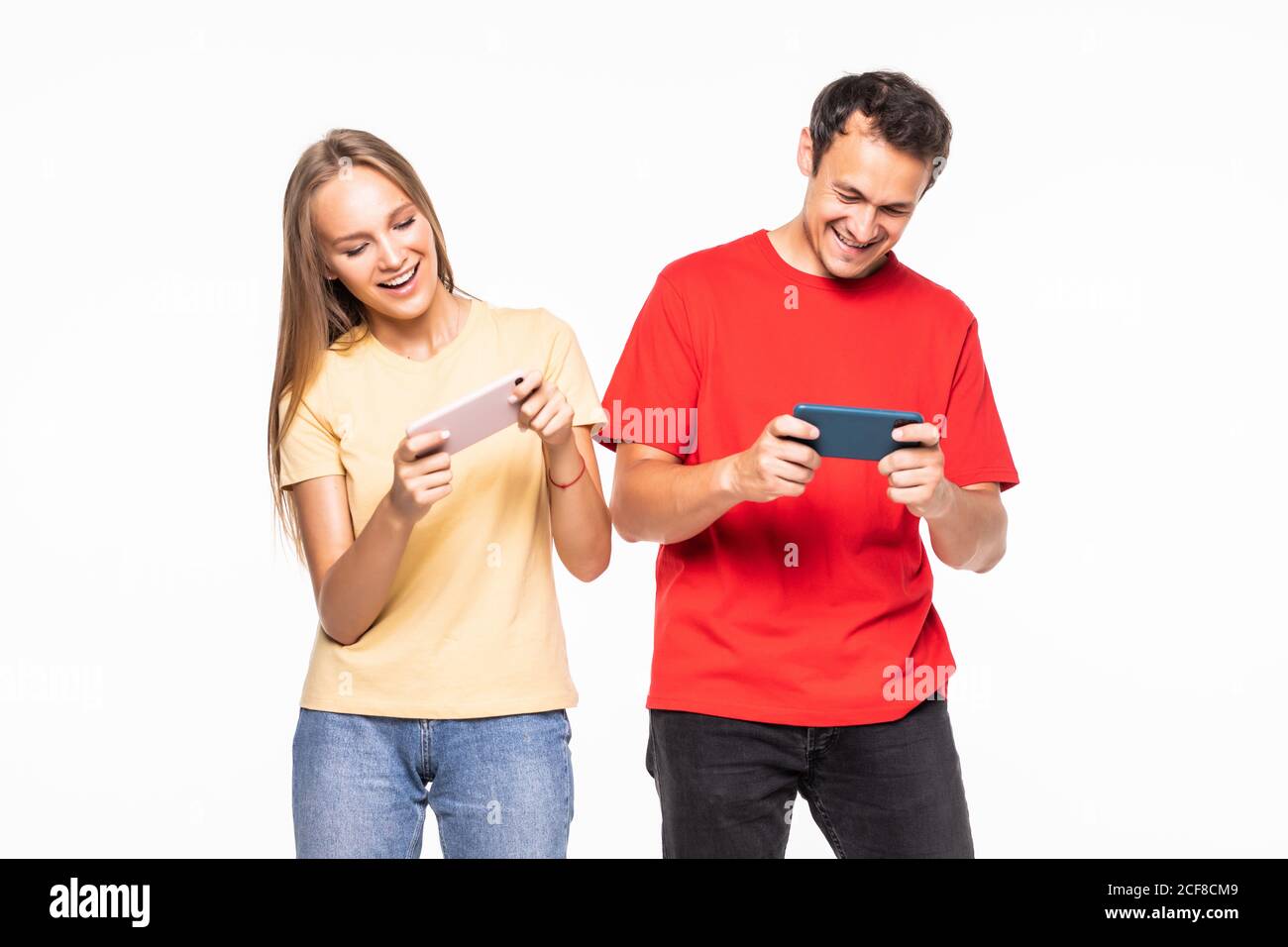Giovane coppia che gioca a videogiochi con telefoni cellulari isolati su uno sfondo bianco. Foto Stock