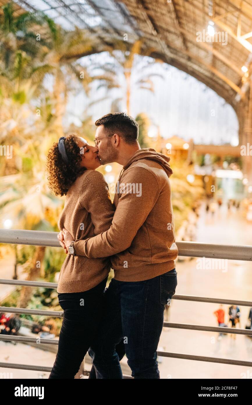 Allegro giovane uomo e donna abbracciando e baciandosi guardandosi mentre si trova all'interno del padiglione illuminato durante la data Foto Stock