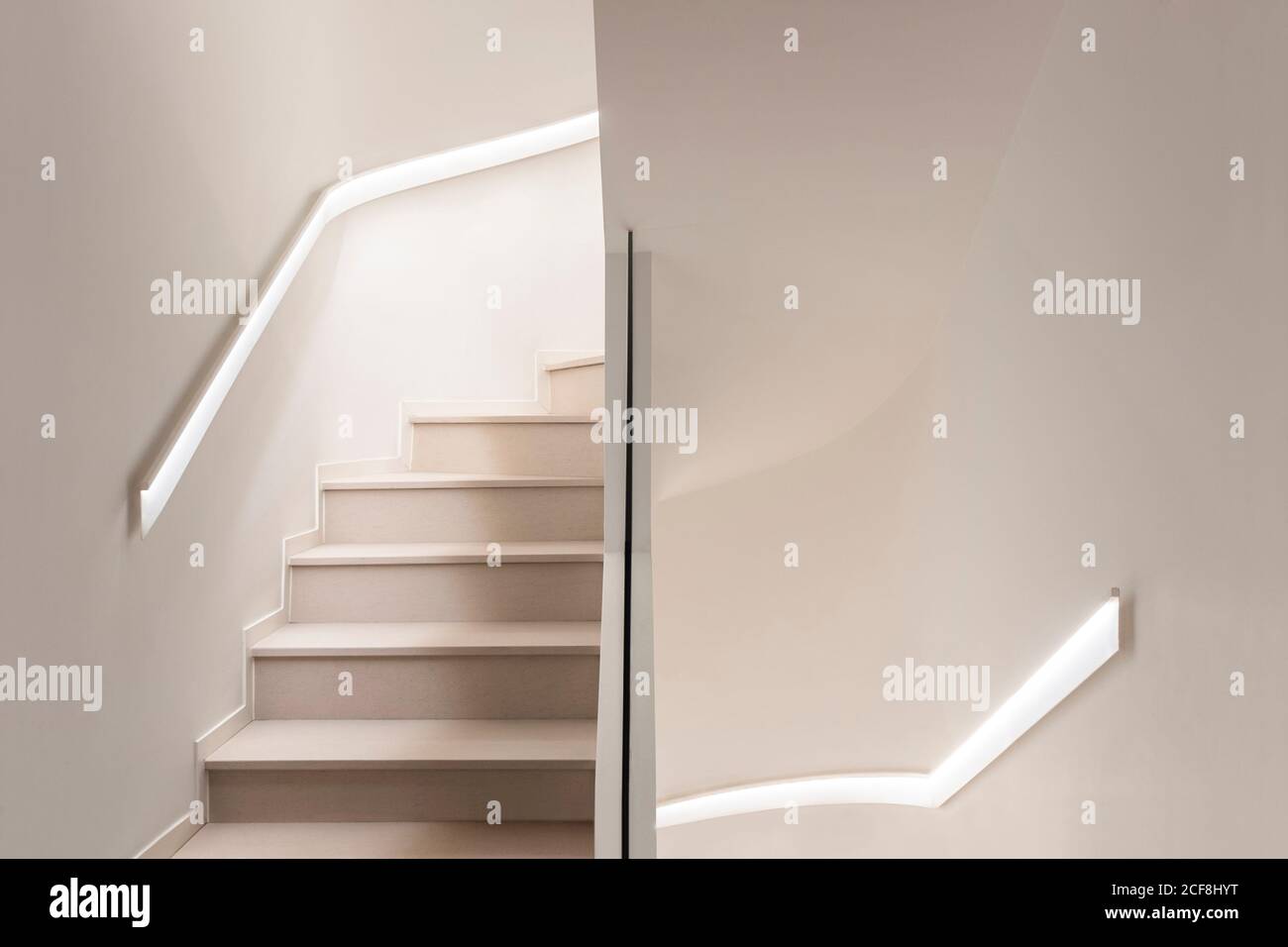 Dall'alto di una moderna scalinata a spirale con ringhiere bianche e. pareti chiare e scale in un edificio contemporaneo Foto Stock
